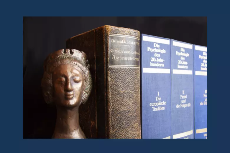 Photo of small bronze bust next to a row of hardback books