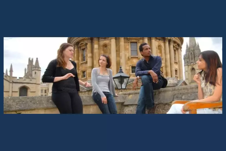 Photo of 4 students gathering on the wall in front of the Bodleian Library
