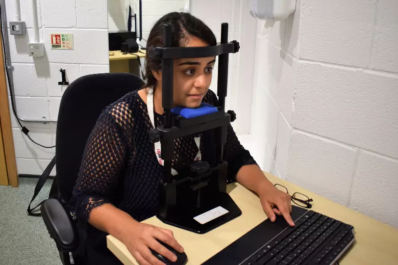 Woman with her face resting on equipment used for vision study